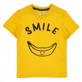 Βαμβακερό μπλουζάκι με τη λεζάντα Smile για ένα μωρό, κίτρινο Idexe 239337 