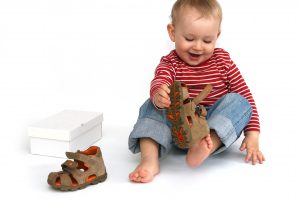 Small,child,tries,to,put,on,his,shoes.,baby,boy