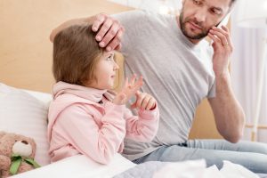 concern.,concerned,dark haired,daddy,holding,a,thermometer,and,talking,on