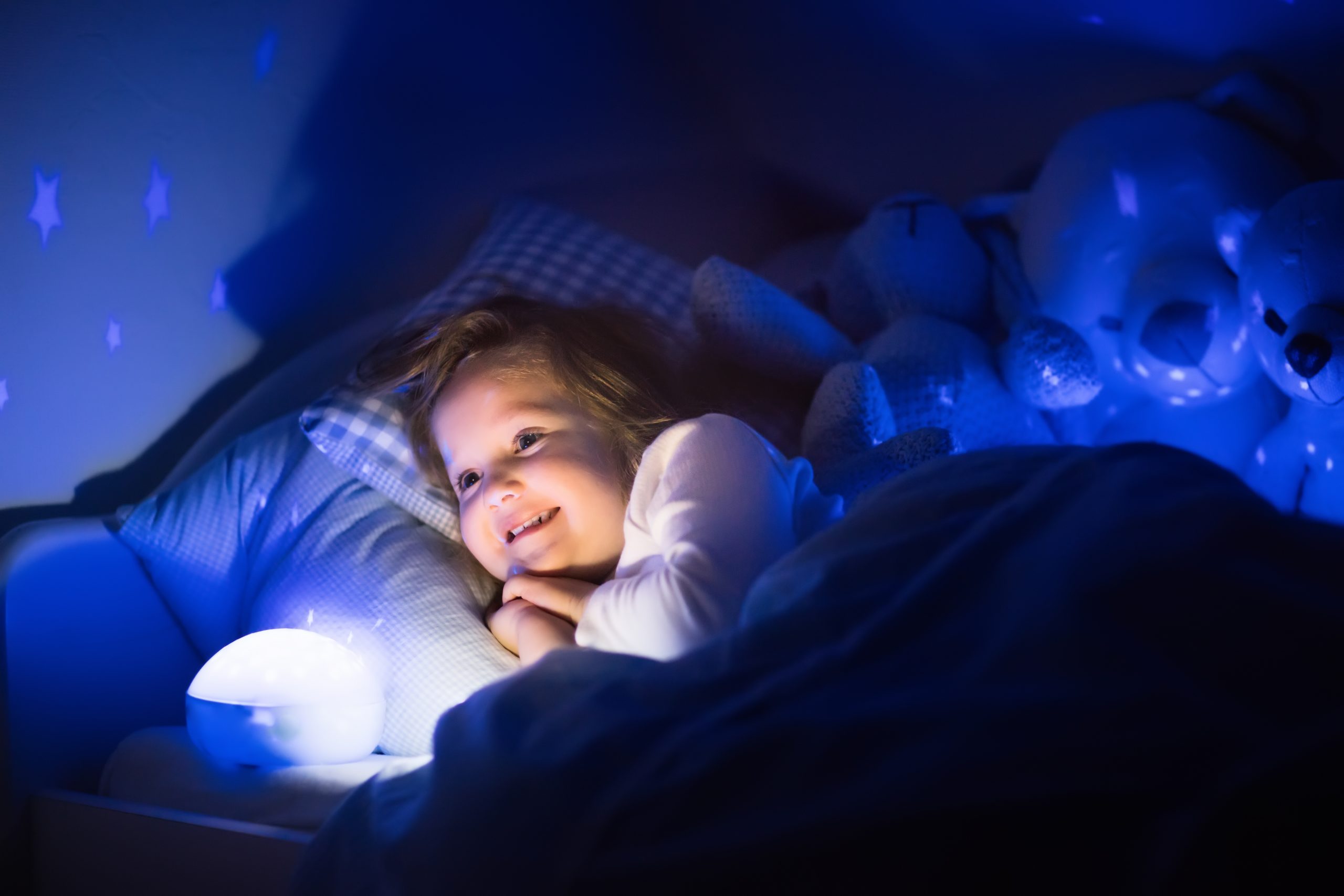 little,girl,reading,a,book,in,bed.,dark,bedroom,with