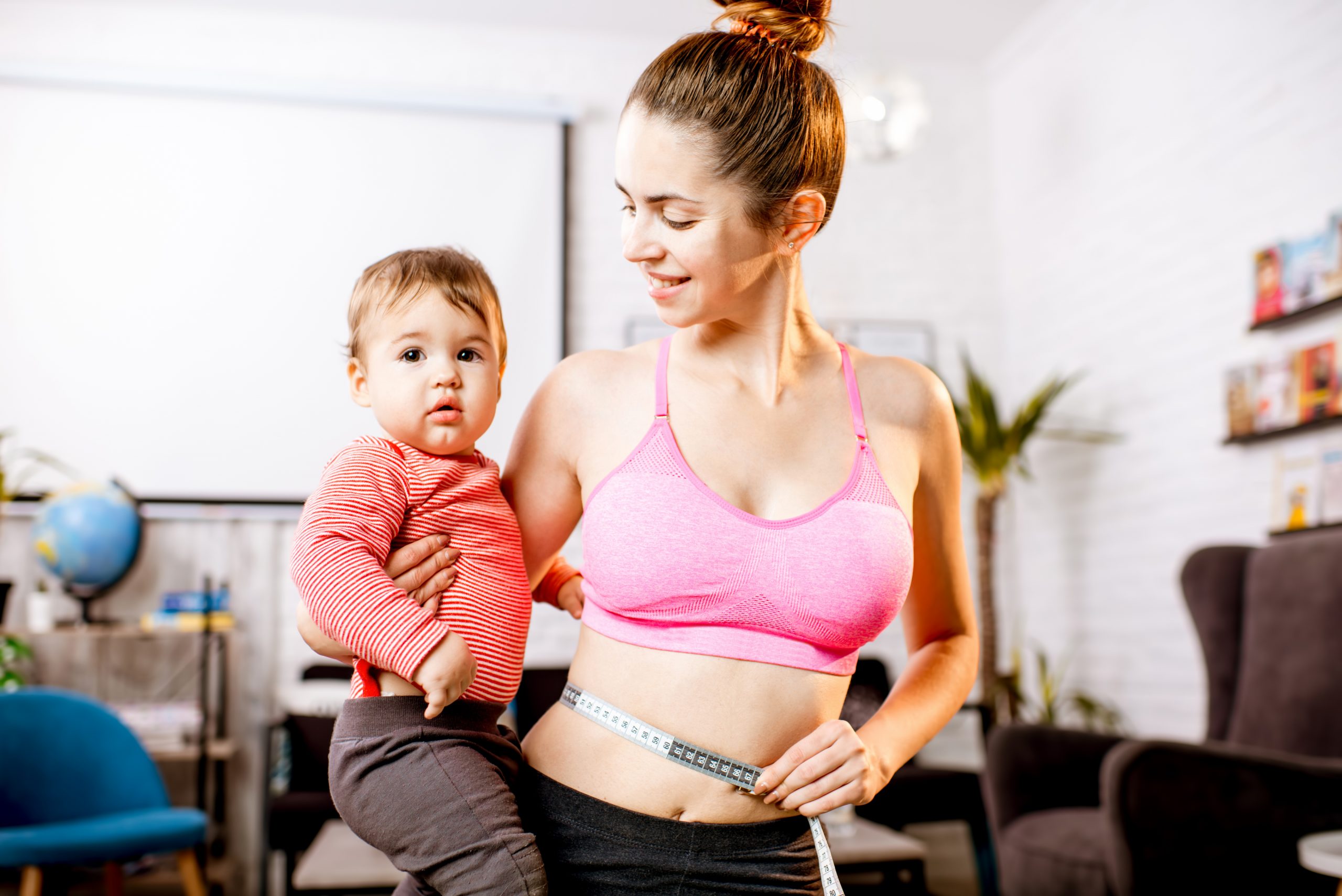 young,mother,in,sportswear,measuring,her,waist,worried,about,her